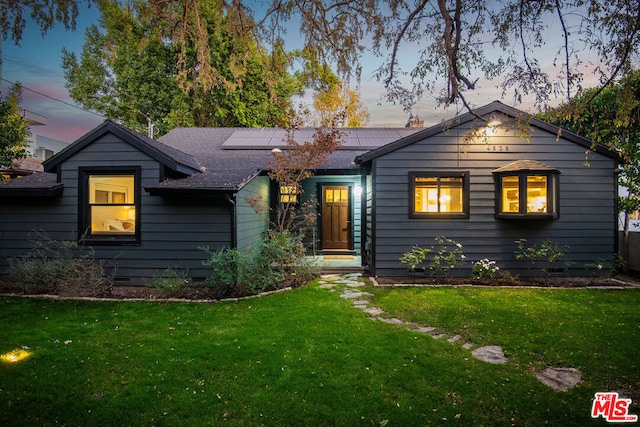 single story home featuring a lawn and solar panels