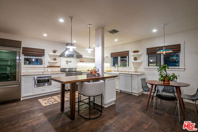 kitchen featuring decorative light fixtures, dark wood-type flooring, white cabinetry, ventilation hood, and high quality appliances