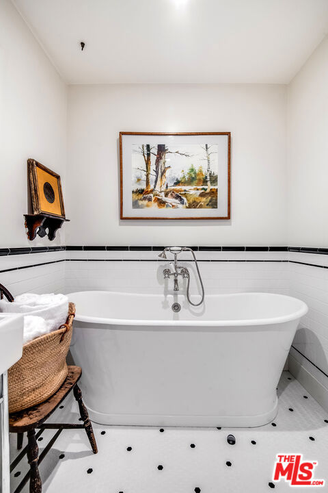 bathroom with a tub to relax in, tile walls, and tile patterned flooring