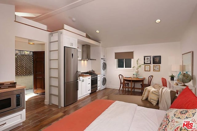 bedroom with lofted ceiling with beams, stainless steel refrigerator, dark wood-type flooring, and stacked washer and dryer