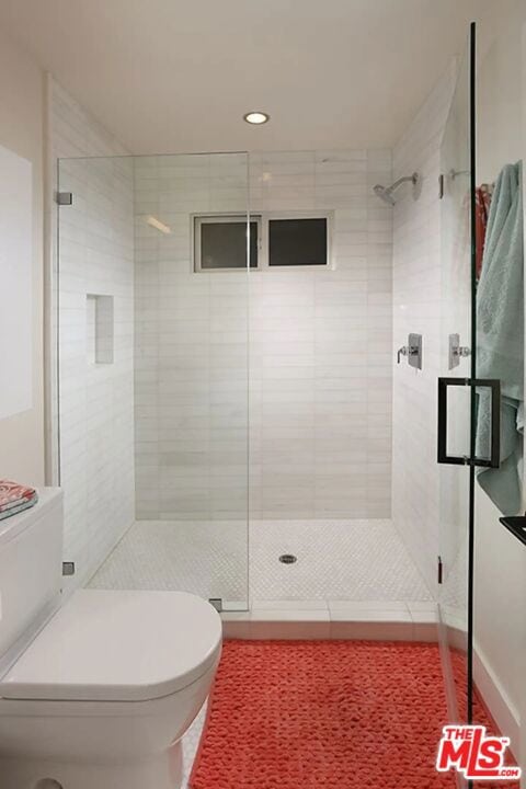 bathroom featuring toilet and a shower with shower door