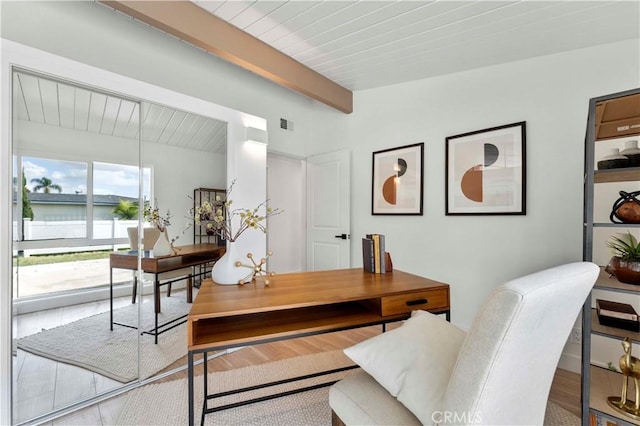 office featuring beam ceiling, a water view, and hardwood / wood-style flooring