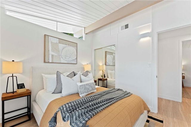 bedroom featuring beamed ceiling, light wood-type flooring, and wood ceiling