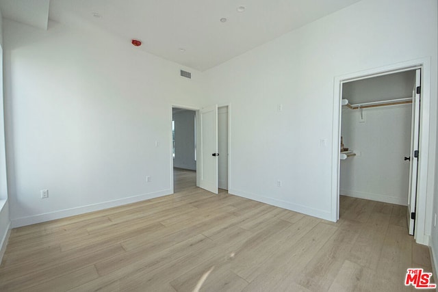 unfurnished bedroom featuring a spacious closet and light hardwood / wood-style floors