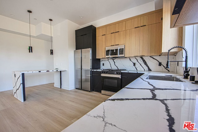 kitchen with sink, hanging light fixtures, stainless steel appliances, light stone countertops, and backsplash