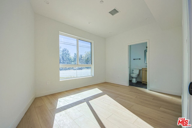 unfurnished bedroom featuring ensuite bath and light hardwood / wood-style flooring