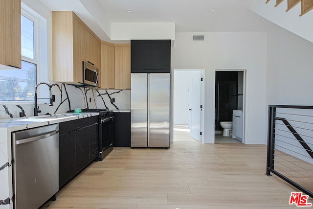 kitchen featuring sink, stainless steel appliances, light hardwood / wood-style floors, light brown cabinetry, and decorative backsplash