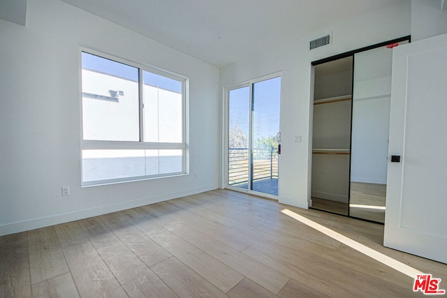 unfurnished bedroom with access to outside and light hardwood / wood-style floors