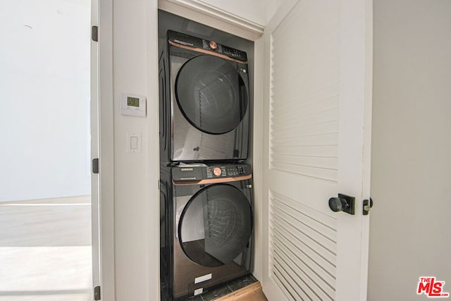 washroom with stacked washer and dryer and wood-type flooring