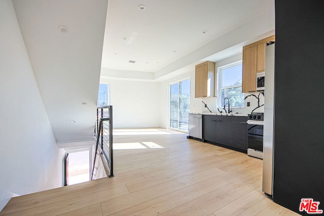 kitchen featuring appliances with stainless steel finishes, sink, light brown cabinets, and light hardwood / wood-style flooring