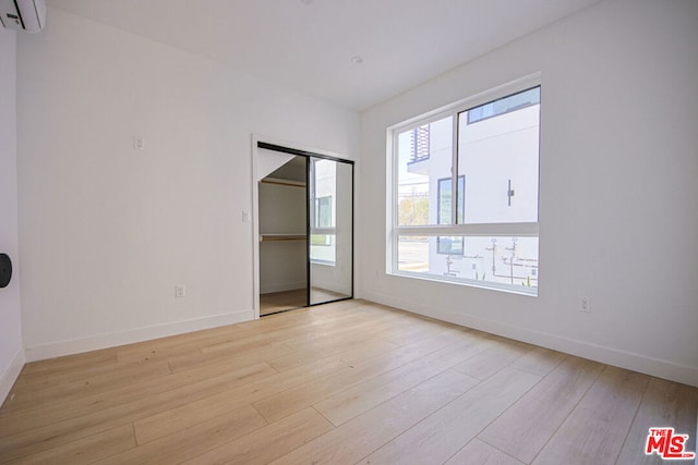 unfurnished room featuring light hardwood / wood-style flooring and a wall mounted AC