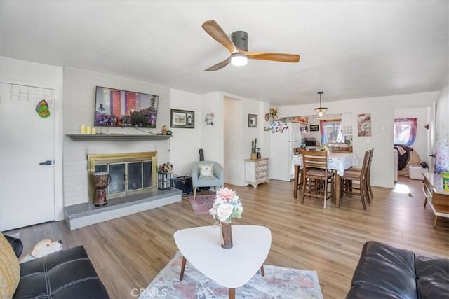 living room featuring a fireplace, hardwood / wood-style flooring, and ceiling fan