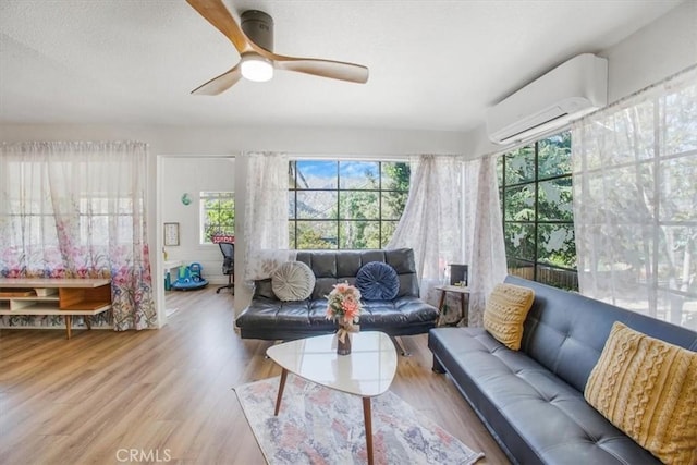 living room featuring hardwood / wood-style floors, an AC wall unit, and ceiling fan