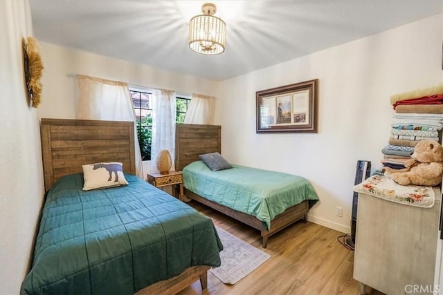 bedroom with light wood-type flooring and an inviting chandelier