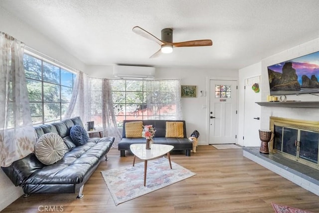 living room featuring a textured ceiling, ceiling fan, light hardwood / wood-style floors, and a wall mounted air conditioner