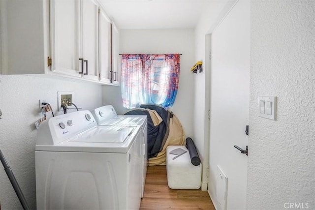 laundry area with cabinets, light wood-type flooring, and washer and dryer