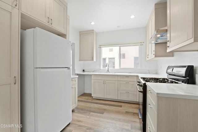 kitchen featuring light stone countertops, light hardwood / wood-style floors, gas range, sink, and white fridge