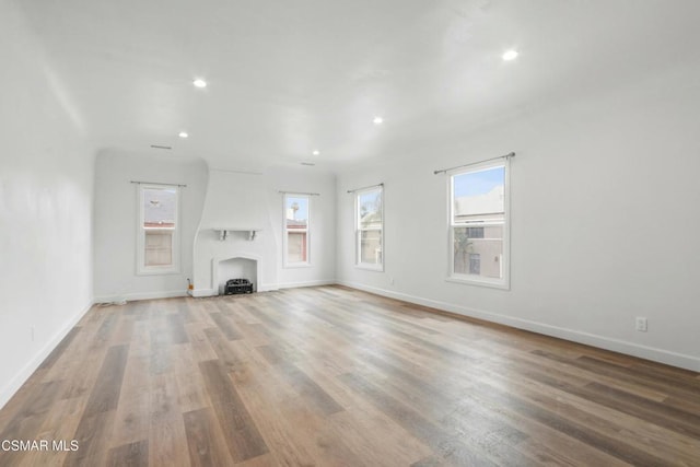 unfurnished living room featuring wood-type flooring and a large fireplace