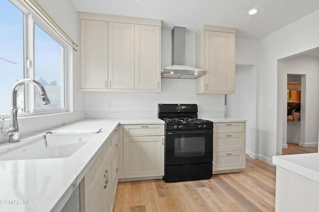 kitchen featuring wall chimney exhaust hood, gas stove, light hardwood / wood-style floors, and sink