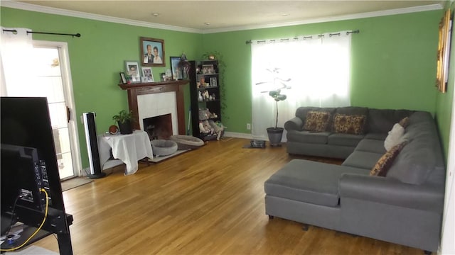 living room featuring a fireplace, hardwood / wood-style flooring, a wealth of natural light, and crown molding