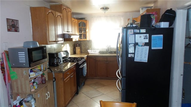 kitchen featuring decorative backsplash, sink, light tile patterned floors, and black appliances