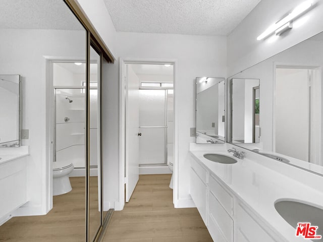 bathroom featuring hardwood / wood-style floors, vanity, toilet, a textured ceiling, and walk in shower