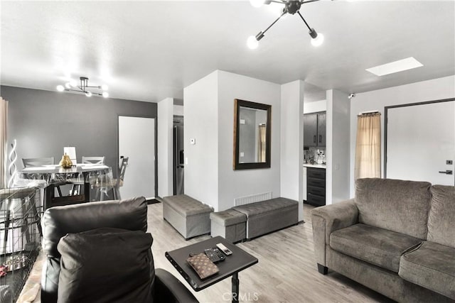 living room with light hardwood / wood-style flooring and an inviting chandelier