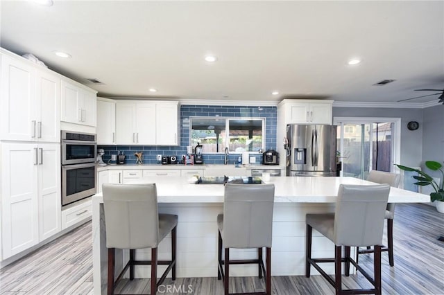 kitchen featuring appliances with stainless steel finishes, light wood-type flooring, and white cabinetry