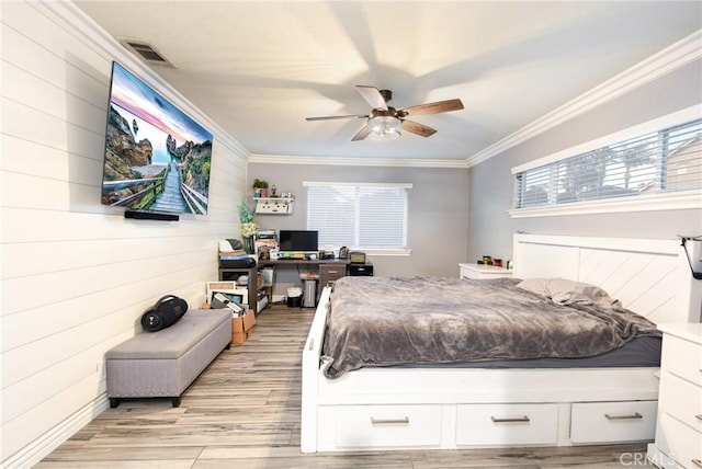 bedroom featuring ceiling fan, light wood-type flooring, crown molding, and wooden walls