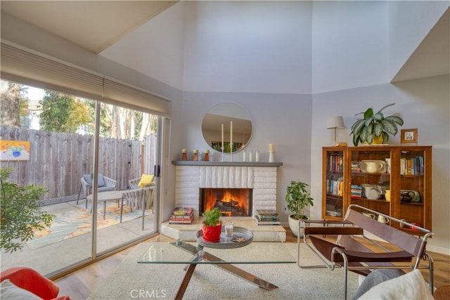 living room featuring wood-type flooring, a high ceiling, and a brick fireplace