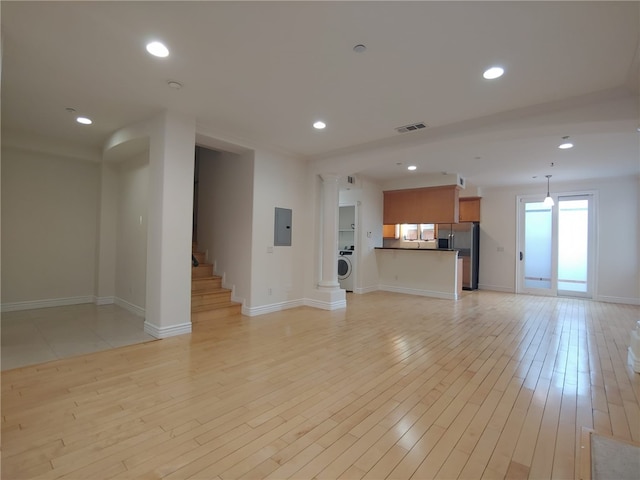 unfurnished living room featuring light hardwood / wood-style floors, washer / dryer, and electric panel