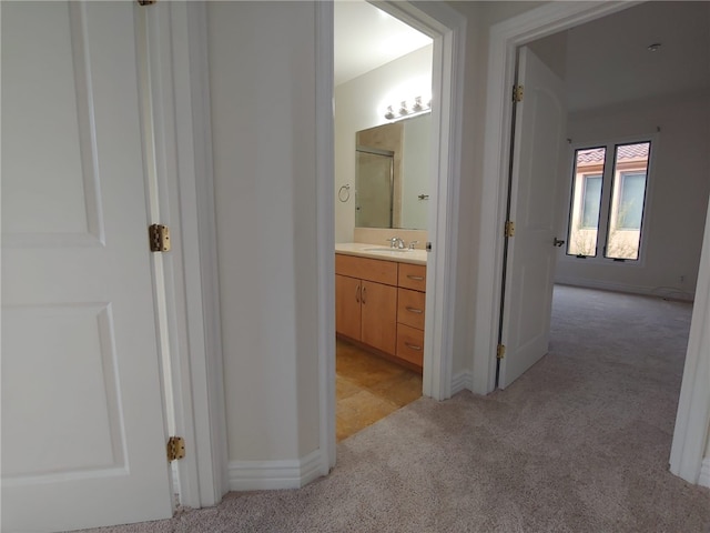 corridor featuring light colored carpet and sink