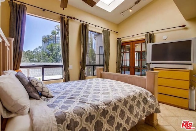 tiled bedroom featuring multiple windows, lofted ceiling with skylight, and rail lighting