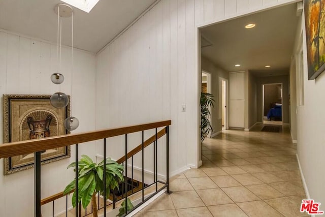 corridor featuring a skylight, wood walls, and light tile patterned flooring