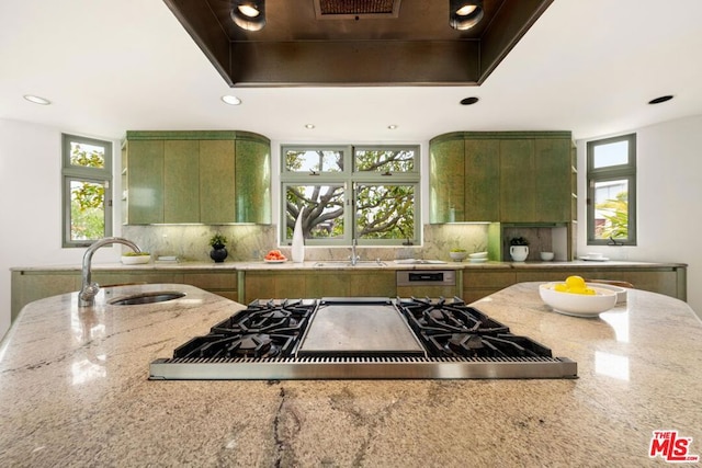 kitchen with light stone counters, plenty of natural light, green cabinets, and stainless steel gas cooktop