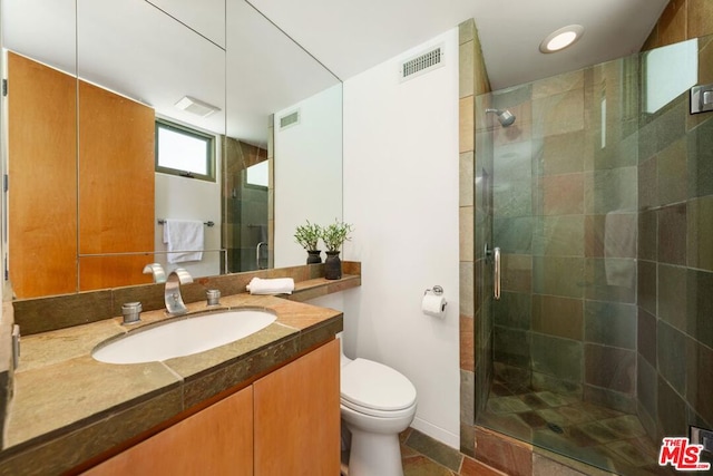 bathroom featuring tile patterned floors, vanity, toilet, and walk in shower