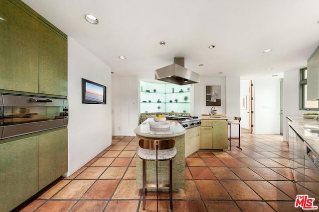 kitchen with a breakfast bar area, island exhaust hood, and green cabinetry