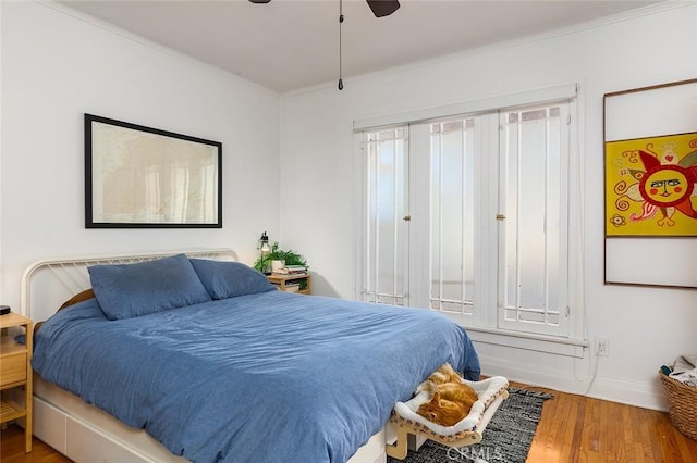 bedroom with wood-type flooring, ceiling fan, and crown molding