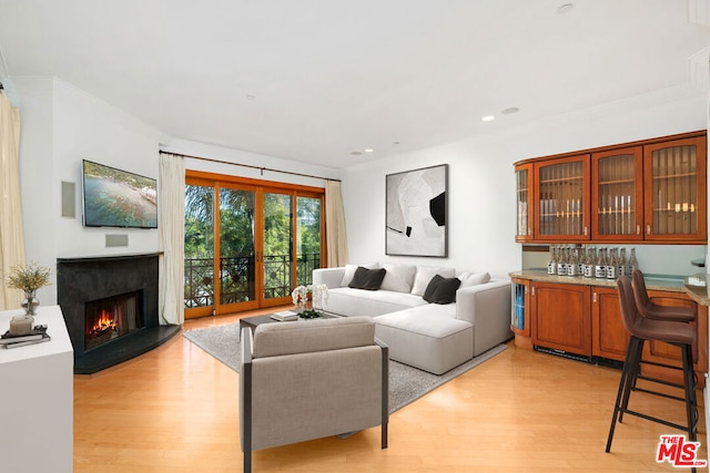 living room featuring bar, a premium fireplace, and light wood-type flooring