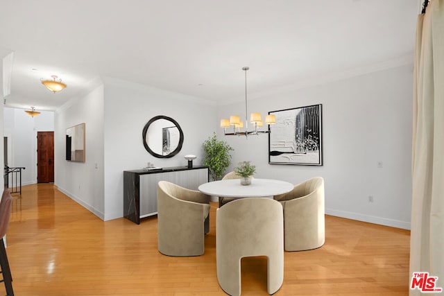 dining room with crown molding, a chandelier, and light hardwood / wood-style flooring