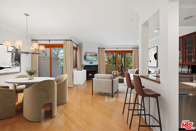 dining space with ornamental molding, light wood-type flooring, and a wealth of natural light