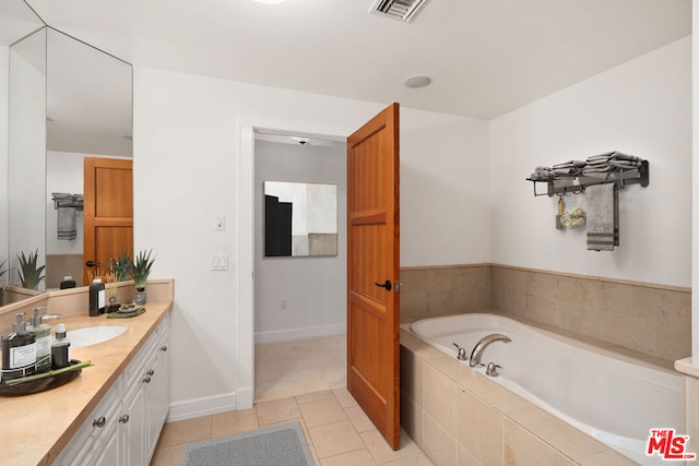 bathroom with tiled tub, vanity, and tile patterned floors