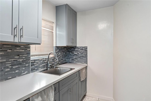 kitchen with gray cabinetry, a healthy amount of sunlight, sink, and backsplash