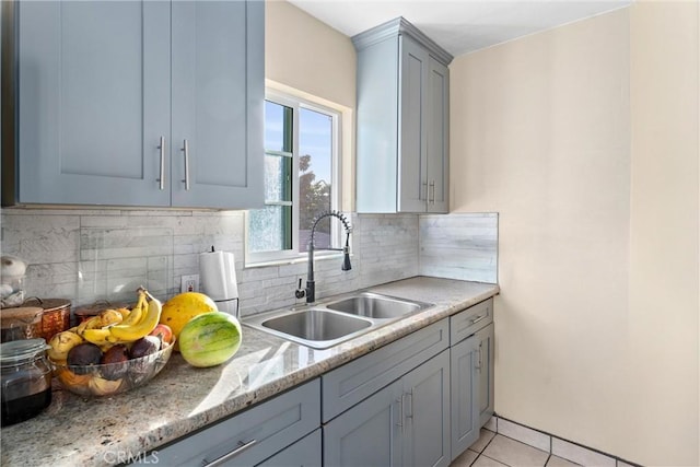 kitchen with decorative backsplash, light tile patterned flooring, light stone counters, and sink