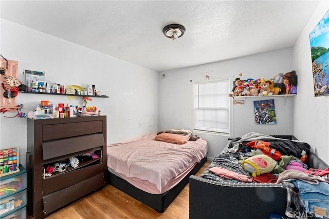 bedroom with a textured ceiling and light hardwood / wood-style flooring