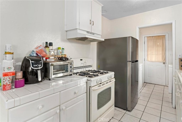 kitchen featuring white cabinets, tile counters, light tile patterned floors, and white range with gas cooktop