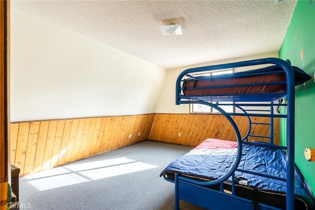 carpeted bedroom with a textured ceiling and wood walls