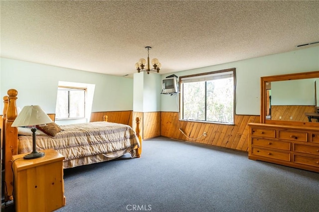 carpeted bedroom with wood walls, a textured ceiling, and a notable chandelier