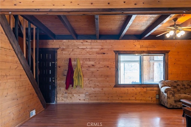 unfurnished living room with wood ceiling, ceiling fan, wooden walls, hardwood / wood-style flooring, and beamed ceiling