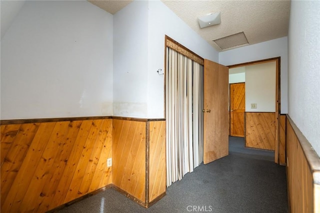 hall with a textured ceiling and wooden walls